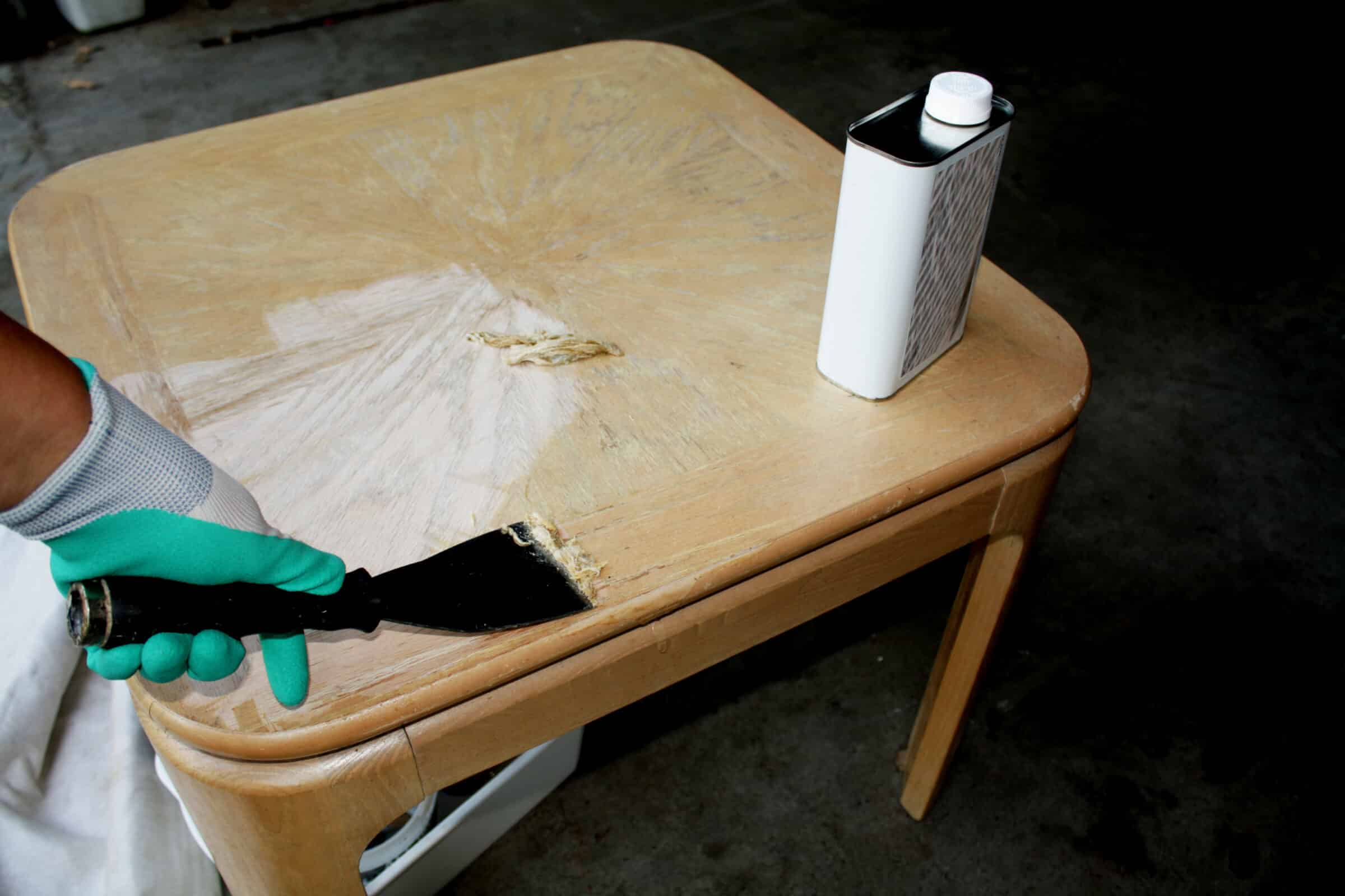 person using paint stripper safely with gloves on and applying it to a wooden side table furniture 