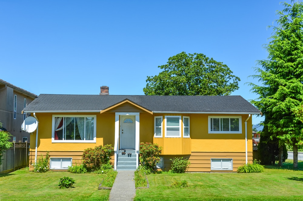 freshly painted yellow home with green grass in front yard