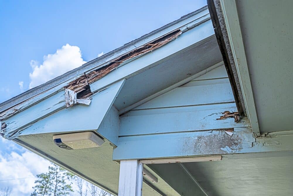 outside of house paint peeling. light blue paint and a blue sky