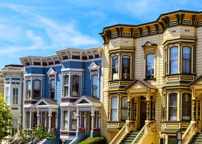 Victorian Style Homes in a Row Highlighting Exterior Paint Colors featuring a light blue, bright blue and cream colored homes