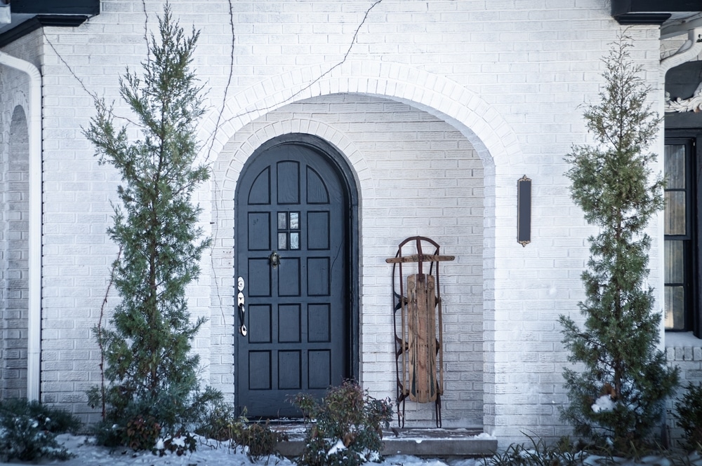 white painted brick with a snow sled and a black door 